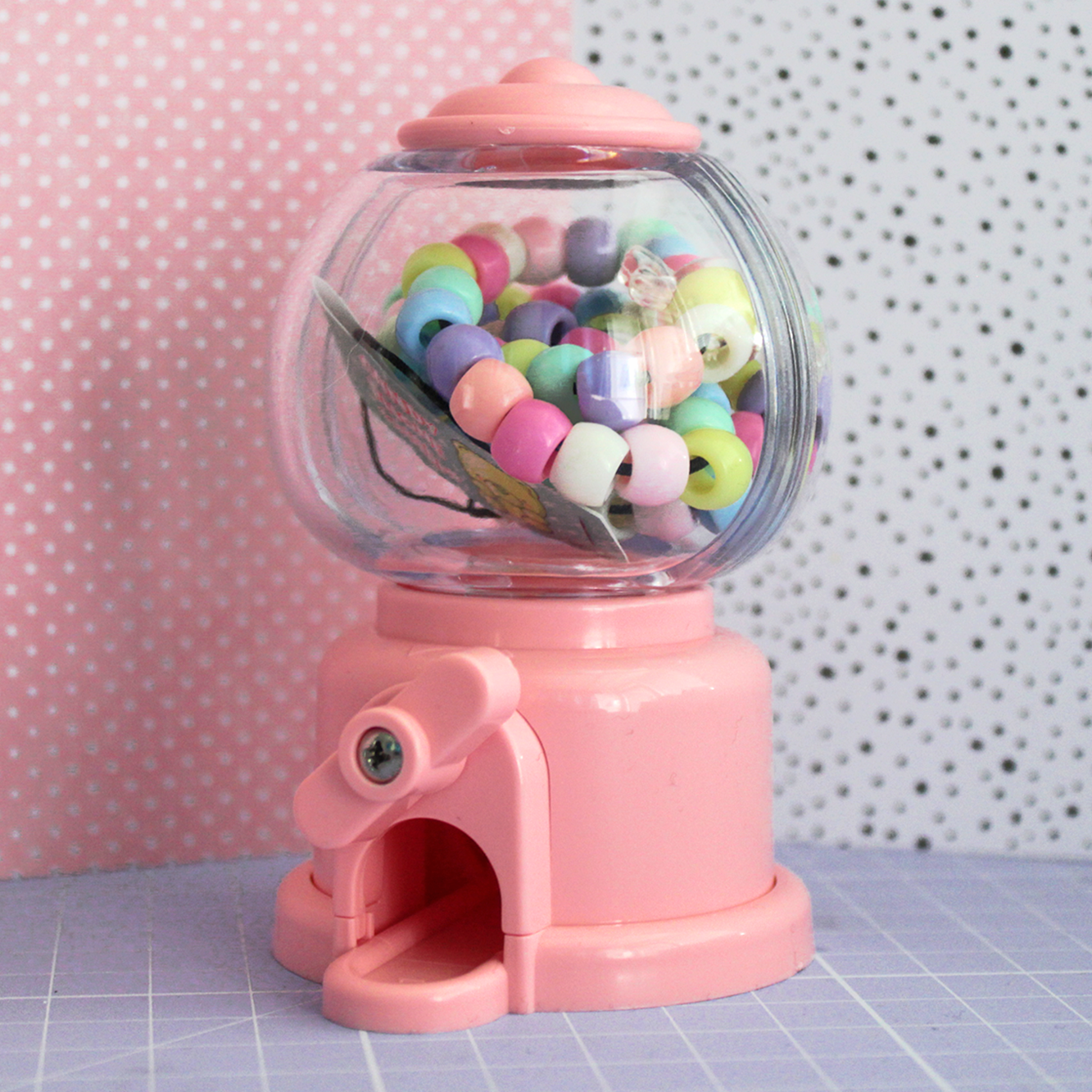 Phone strap made out of colored beads and an acrylic gummy bear charm inside a candy dispenser