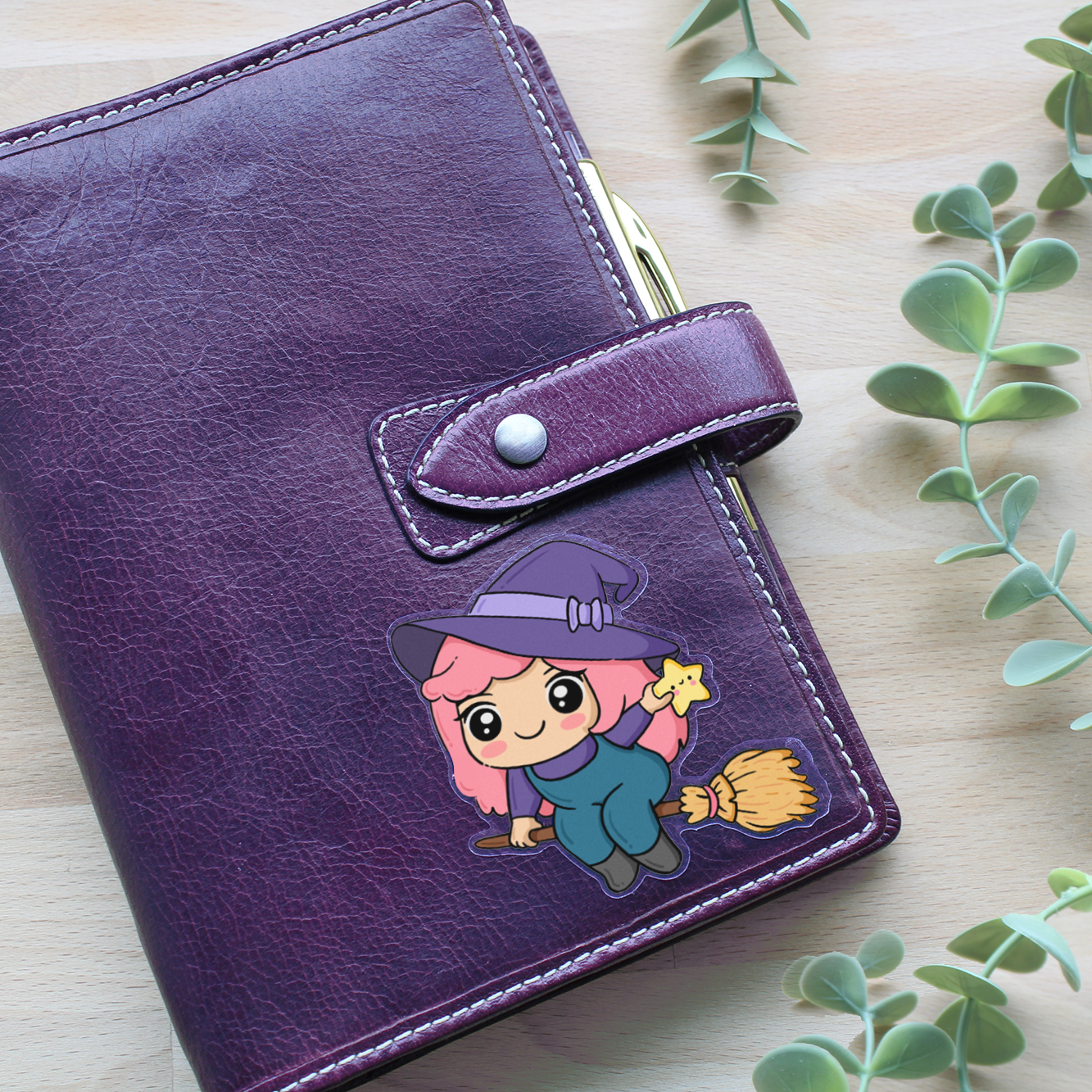 Hand drawn vinyl sticker on an angeda of a kawaii girl with pink hair dressed as a witch flying on a broom holding a star and wearing a hat