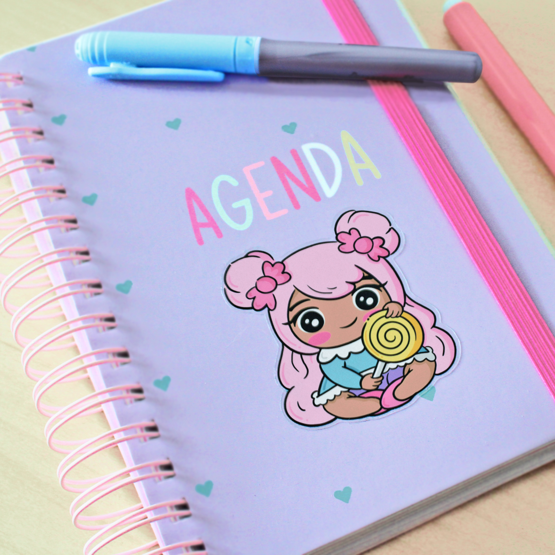 Hand drawn vinyl sticker on an agenda of a kawaii girl with pink hair holding a lollypop